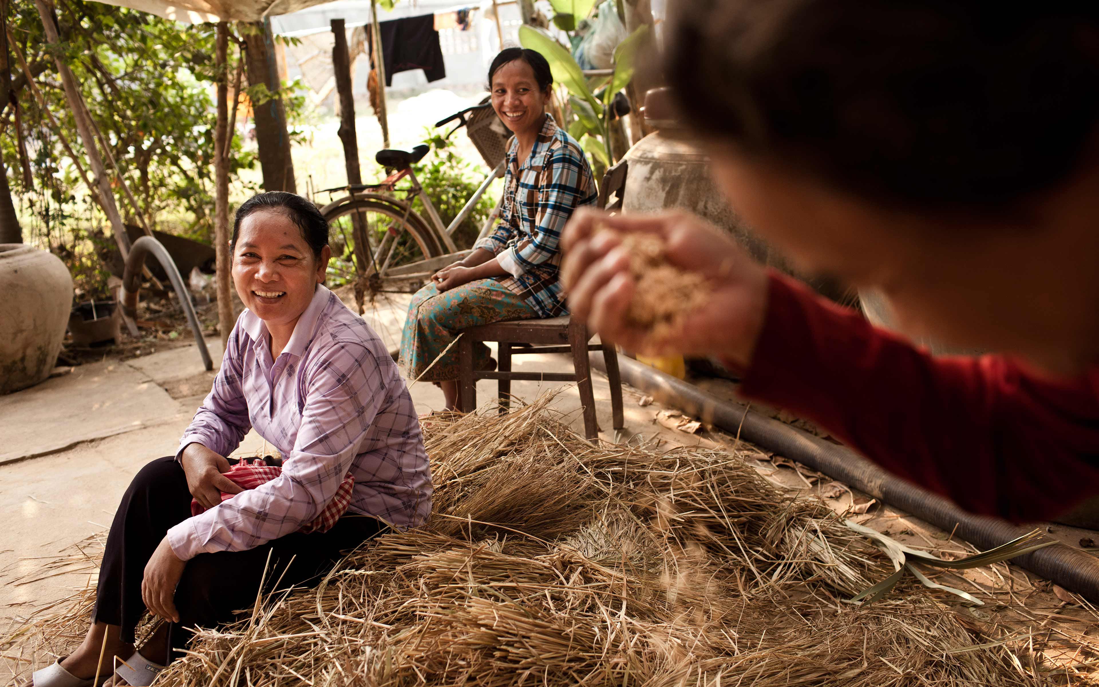 Khek Koeu (left) visits with neighbors at her home in Pursat province. She and six other farmers in her village got specialized training to become rice seed producers, which helps area farmers to access high-quality seed.