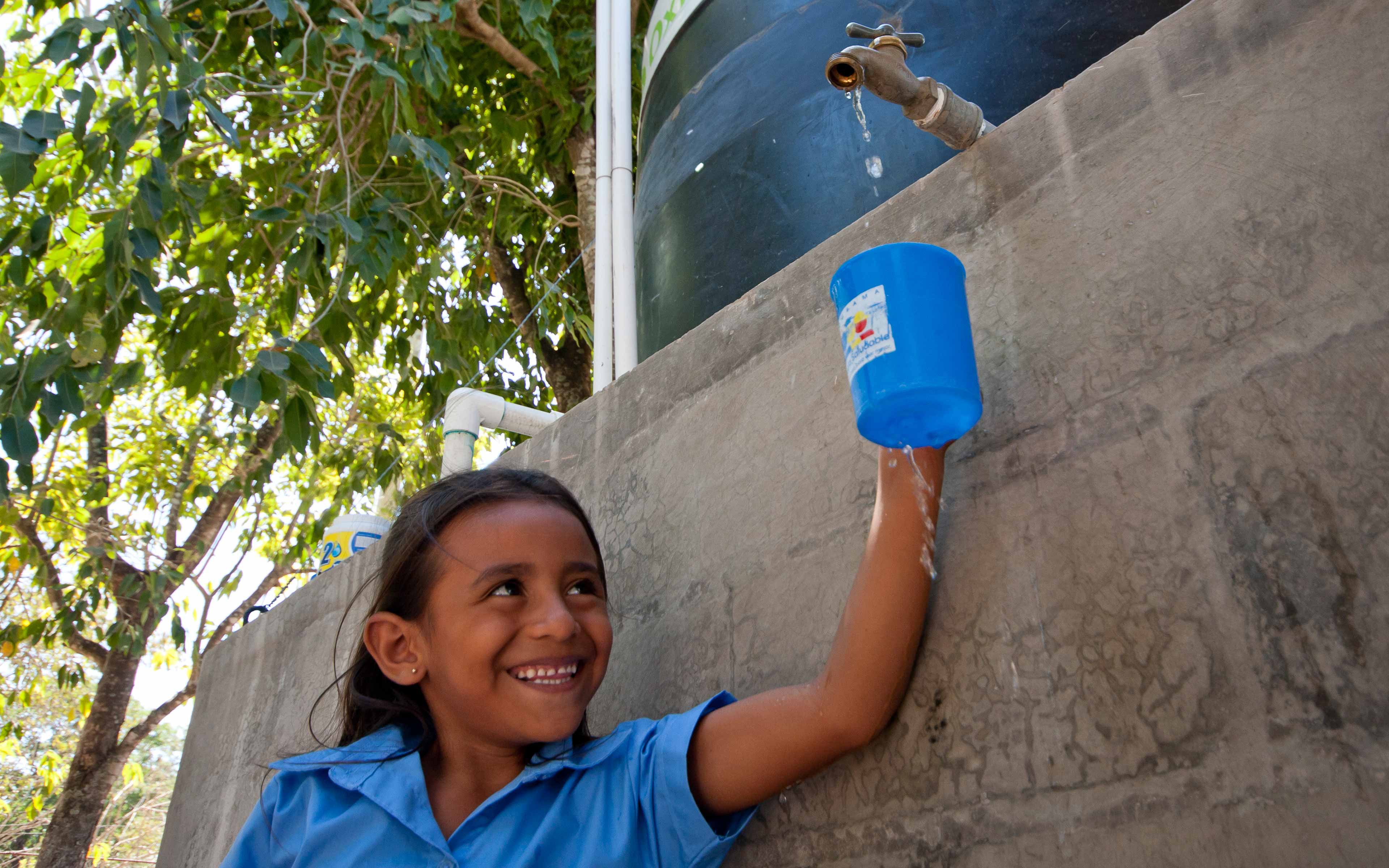 A girl draws water from a community “healthy well” in Zacatecoluca, El Salvador, built by Oxfam partner PRO-VIDA and designed to resist contamination from floodwater. “Before we had the well, there was a lot of diarrhea; the number of cases has gone way down,” says  Estela Umaña, a resident of El Salitral.