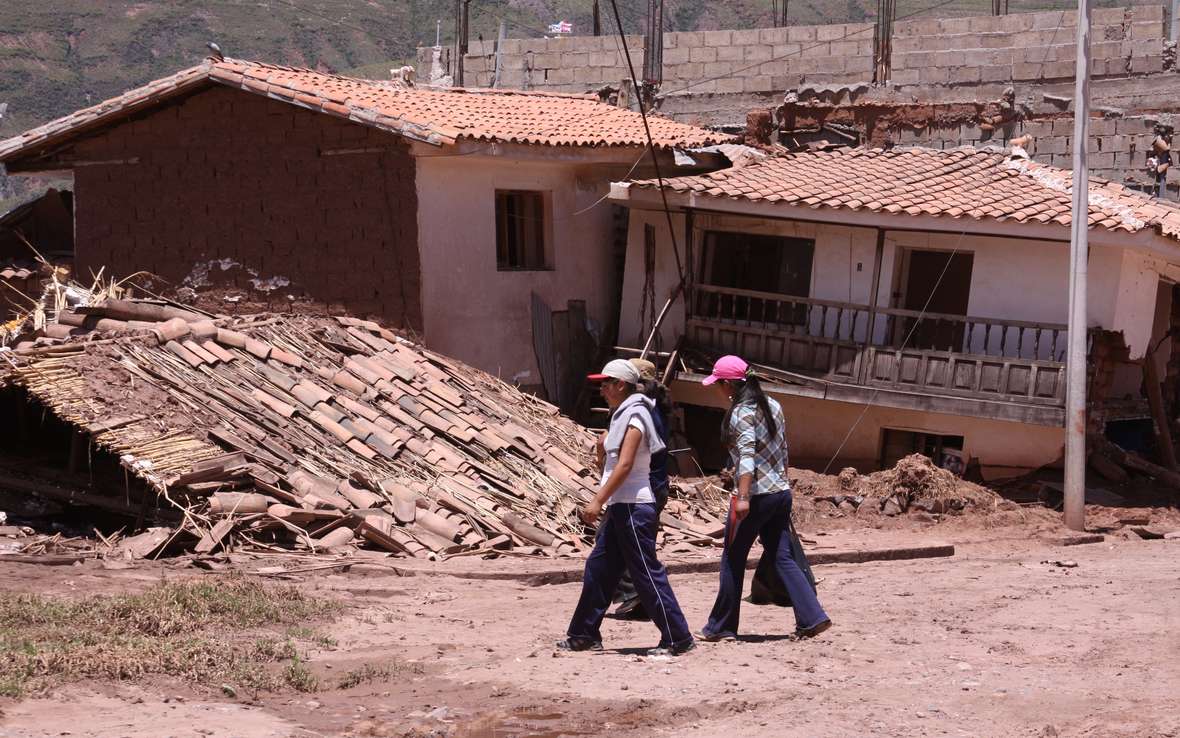 girls-walking-in-front-of-destroyed-houses.jpg