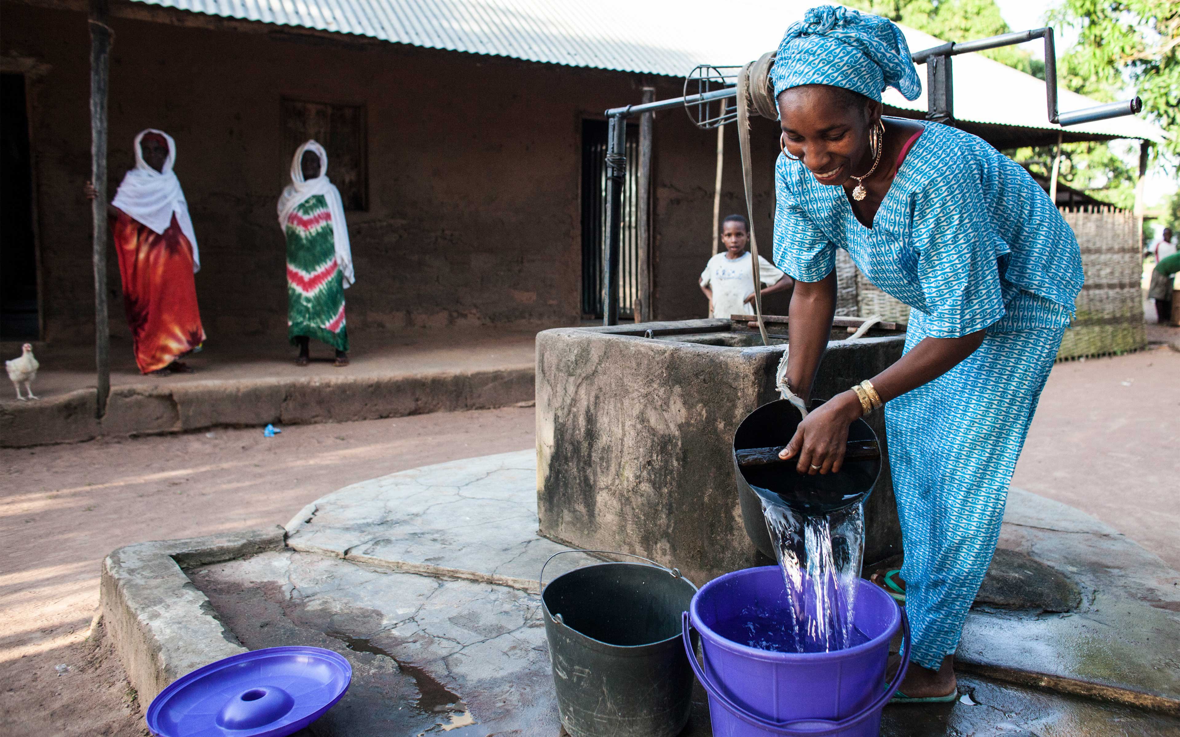 Ussai Balde gathers water at a well in Cuntabane, Guinea-Bissau—a town that borders Ebola-affected Guinea. During the epidemic, NADEL provided hygiene kits to community members here, as well as border surveillance and information about Ebola prevention.