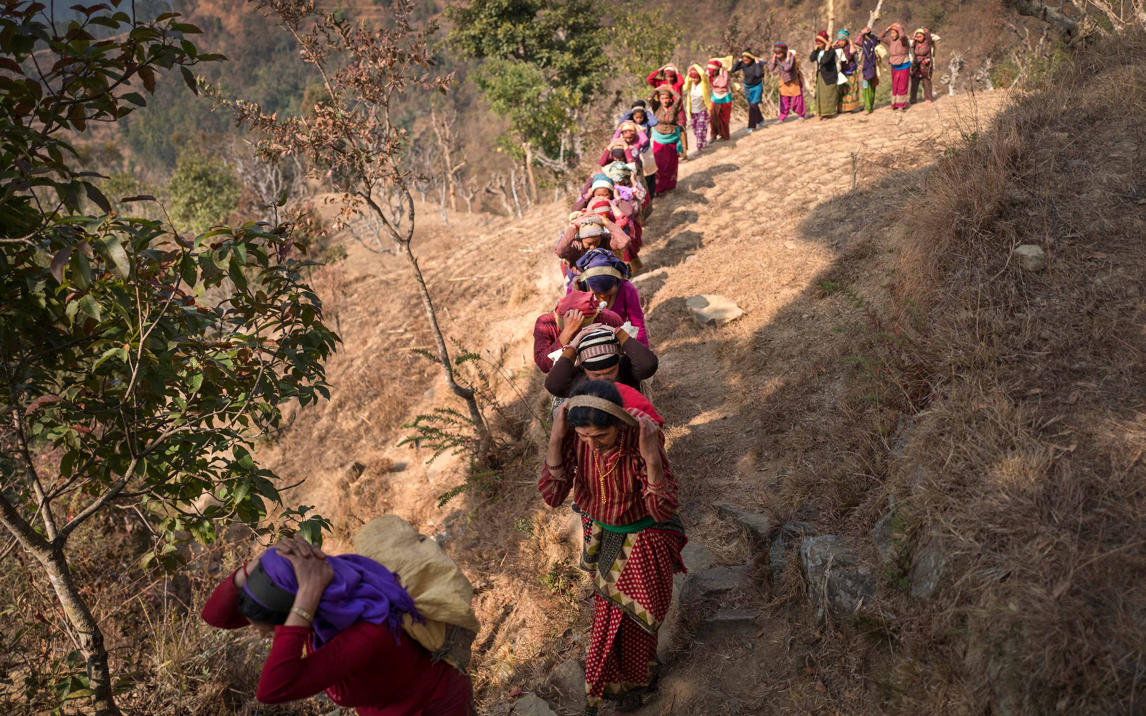 Lugging heavy stones on their backs, women help to build a trail that will allow community members easier passage between their villages in Nepal. The trail is part of an Oxfam cash-for-work initiative designed to improve the community while providing people with income.