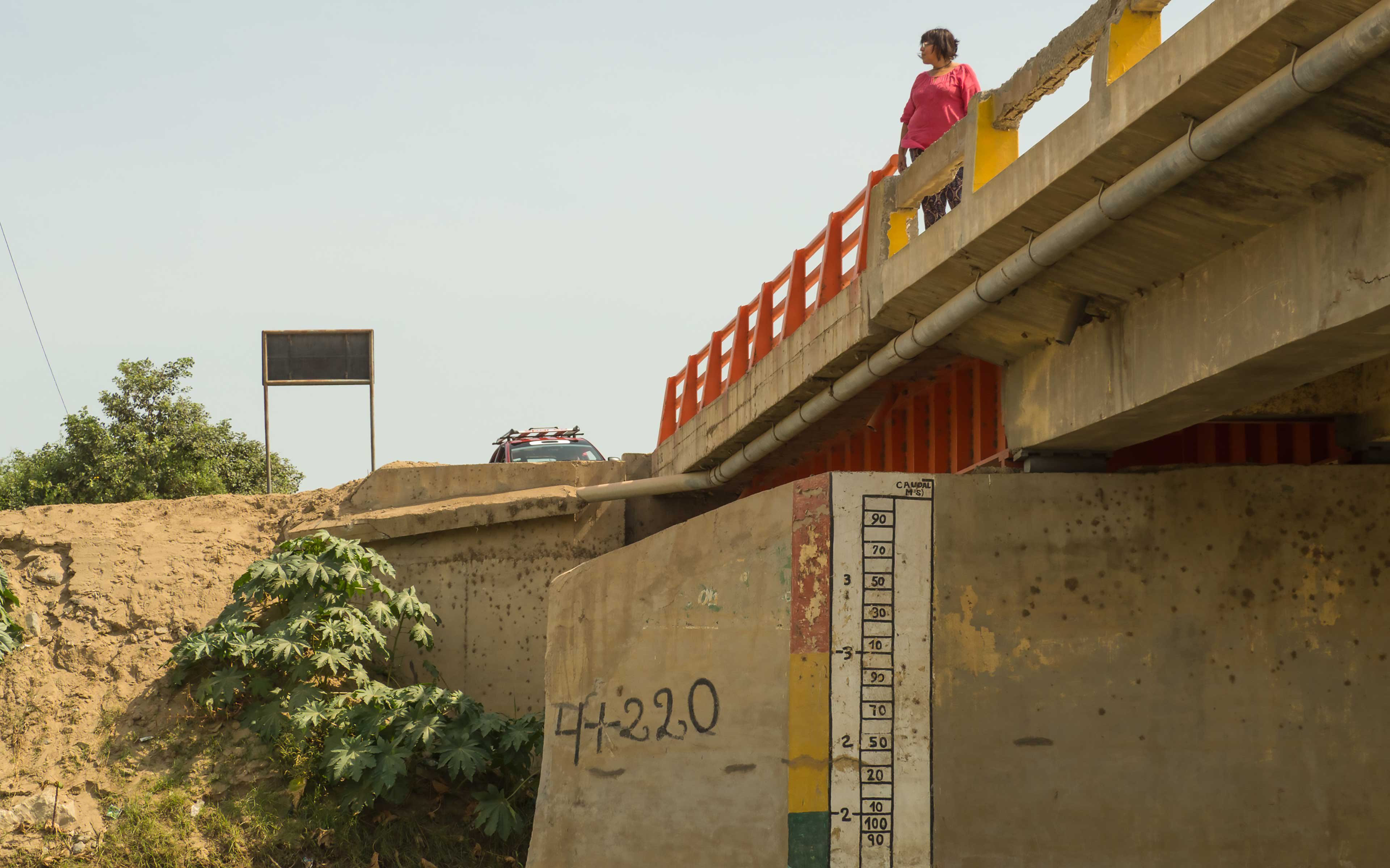 Rosa Rivero stands on a bridge over the La Leche river. Measurements painted on the bridge are part of the Las Juntas flood early warning system.
