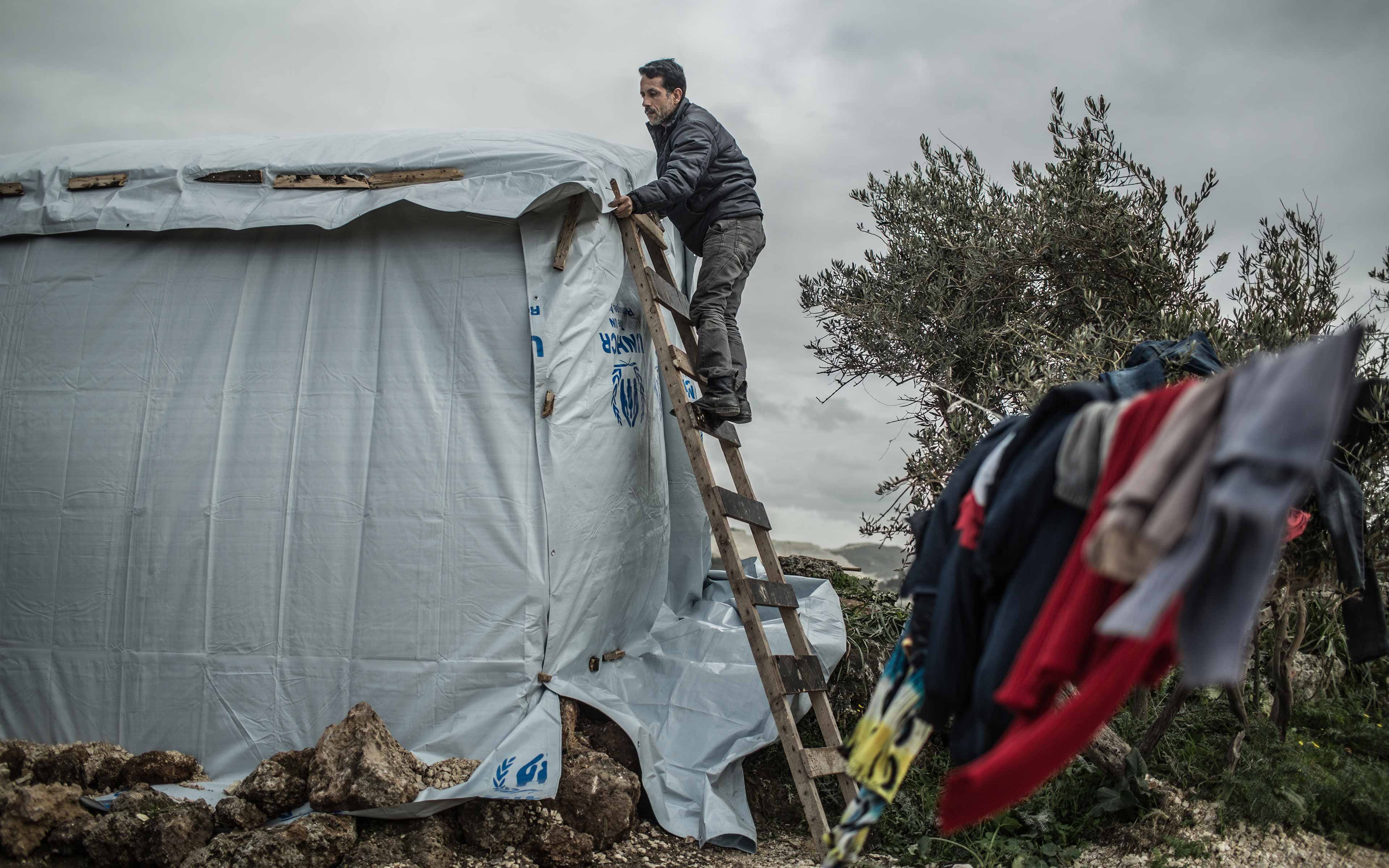 Ahmed works on a shelter made of wood and plastic sheeting in an informal settlement in northern Lebanon that is entirely dependent on humanitarian aid. He fled from Hasaka, Syria, with his family in 2012.